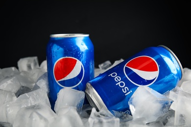 Photo of MYKOLAIV, UKRAINE - FEBRUARY 11, 2021: Cans of Pepsi on ice cubes against black background