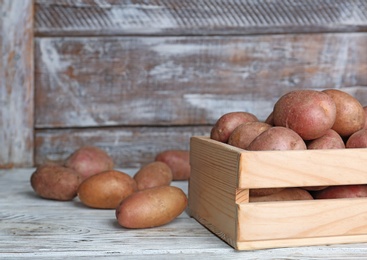 Photo of Crate with fresh ripe organic potatoes on wooden table