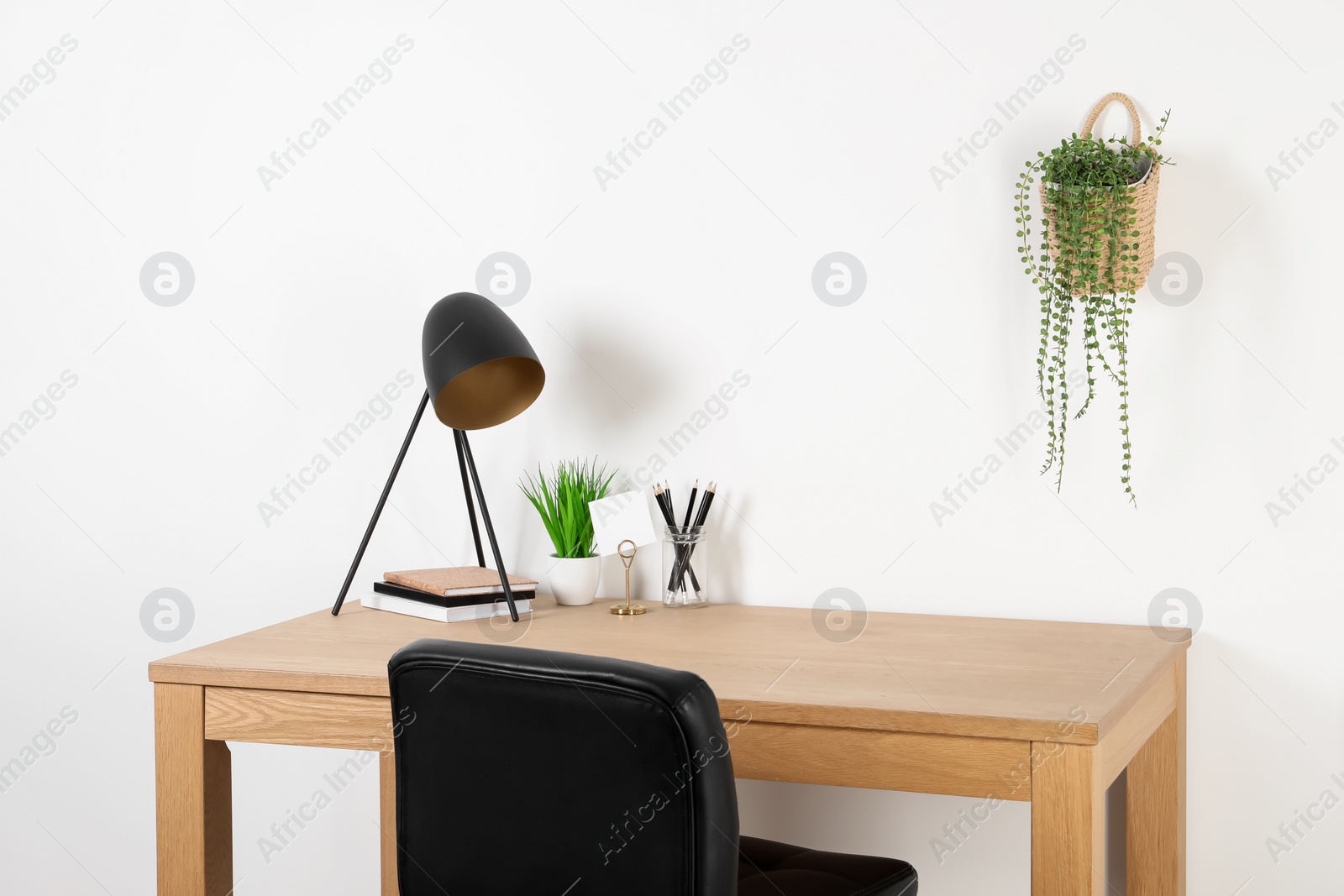 Photo of Comfortable workplace with wooden desk near white wall at home