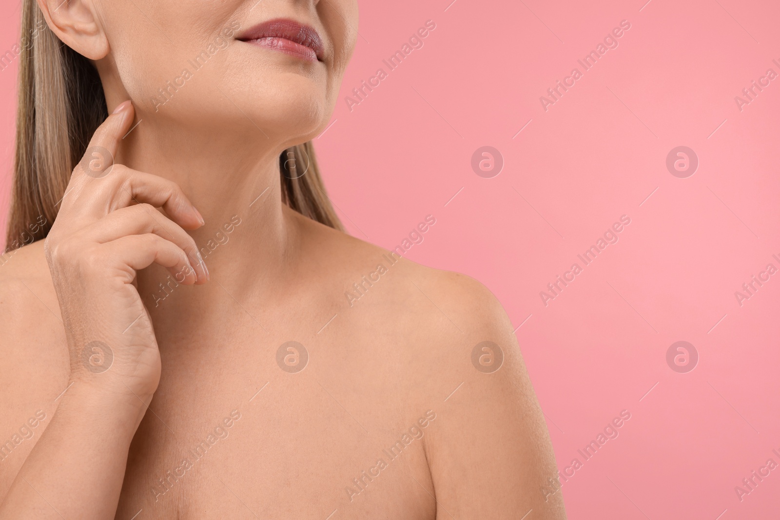 Photo of Mature woman touching her neck on pink background, closeup. Space for text