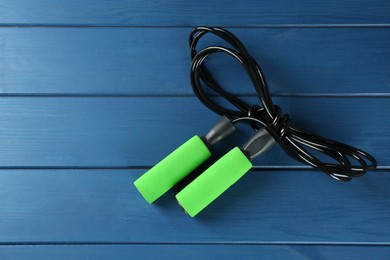 Skipping rope on blue wooden table, top view. Sports equipment