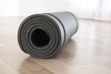 Photo of Rolled grey yoga mat on floor indoors