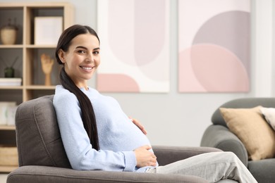 Happy pregnant woman on armchair at home