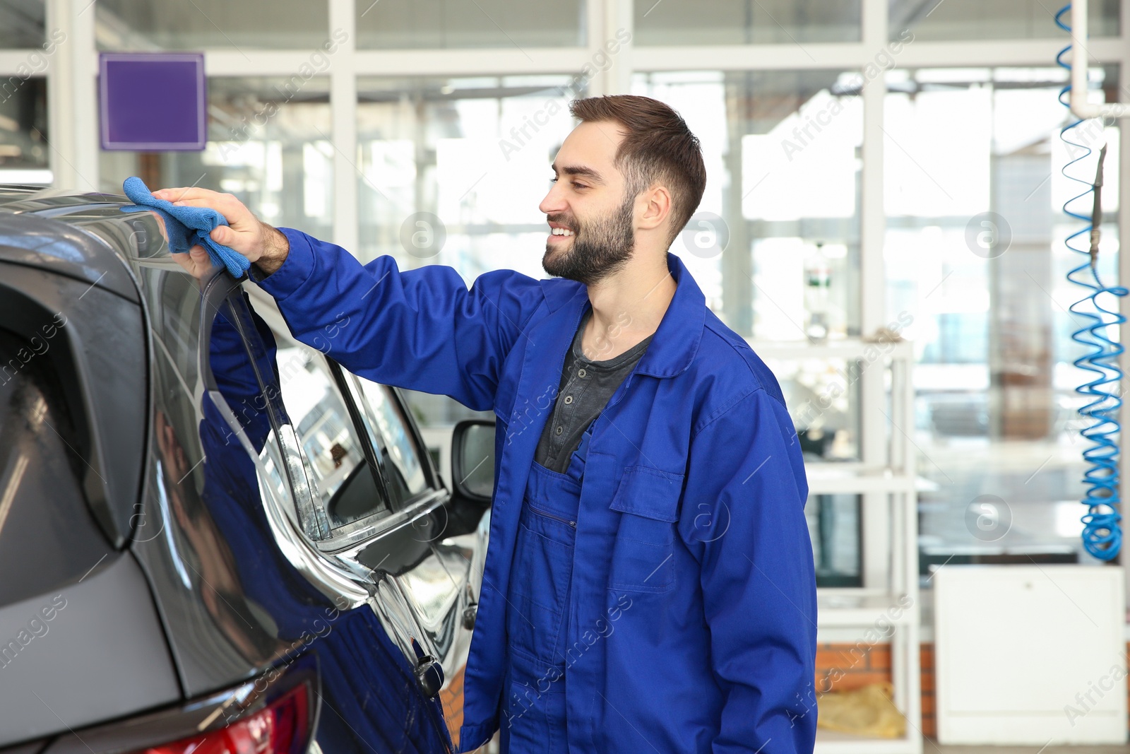 Photo of Worker cleaning automobile with rag at car wash