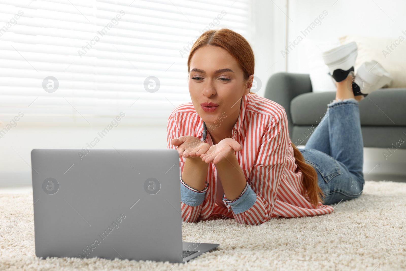 Photo of Woman blowing kiss during video chat via laptop at home. Long-distance relationship