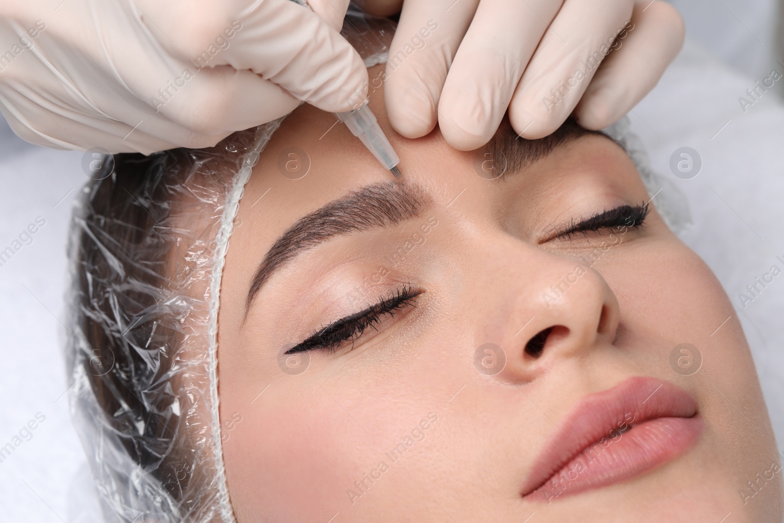 Photo of Young woman during procedure of permanent eyebrow makeup, closeup