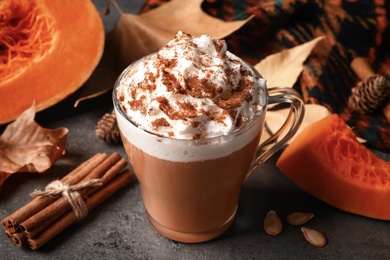 Photo of Delicious pumpkin latte and ingredients on grey table, closeup