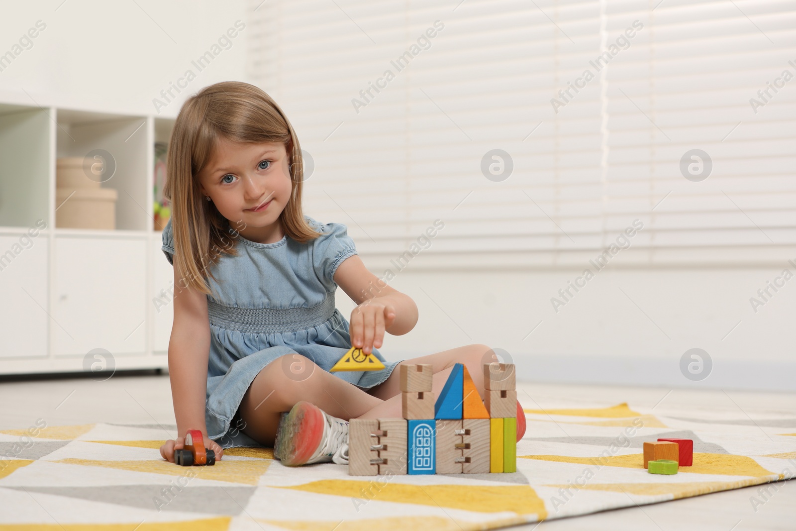 Photo of Cute little girl playing with wooden toys indoors, space for text