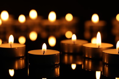 Burning candles on surface in darkness, closeup