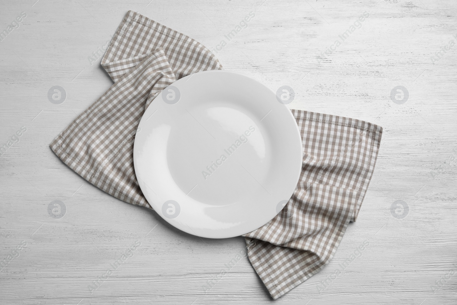 Photo of Empty plate and napkin on white wooden background, flat lay