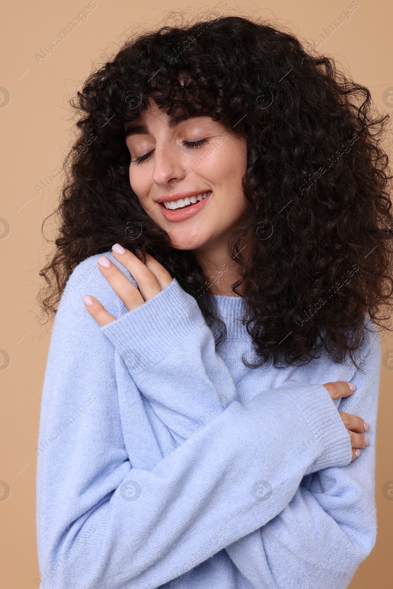 Photo of Happy young woman in stylish light blue sweater on beige background