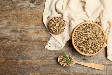 Flat lay composition with bowls and spoon of hemp seeds on wooden background. Space for text