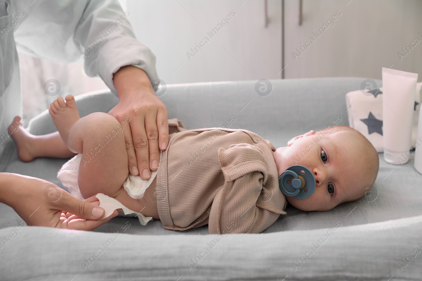 Photo of Mother changing baby's diaper on table in room, closeup