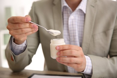 Photo of Young man with tasty yogurt at table, closeup