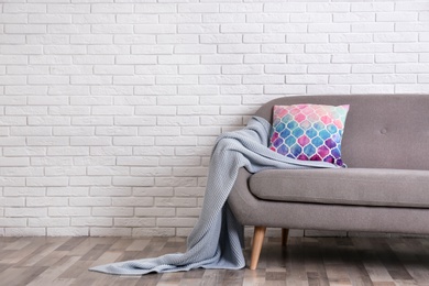 Photo of Minimalist living room interior with cozy sofa, pillow and plaid near brick wall. Space for text