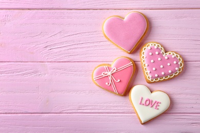 Decorated heart shaped cookies on wooden background, flat lay with space for text. Valentine's day treat