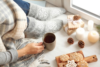 Photo of Woman relaxing with cup of hot winter drink near window. Cozy season