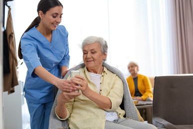 Photo of Care worker giving water to elderly woman in geriatric hospice