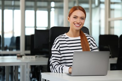 Photo of Happy woman using laptop at table in office, space for text