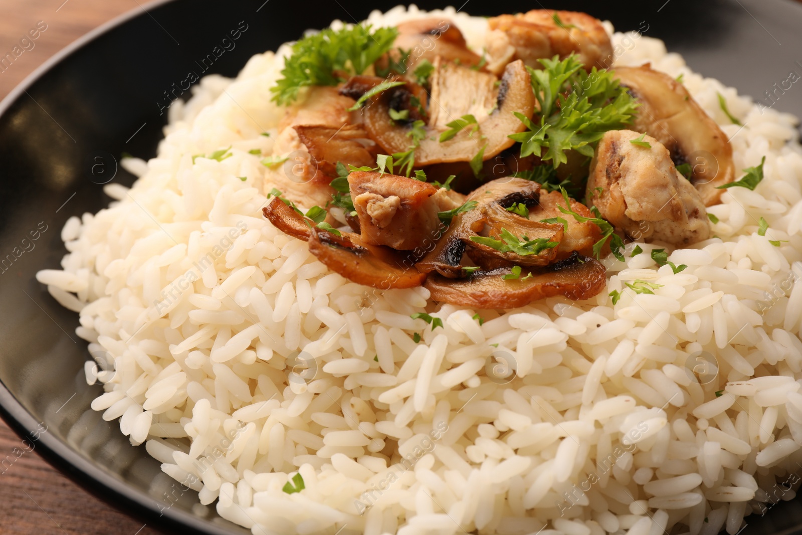 Photo of Delicious rice with mushrooms and parsley on plate, closeup