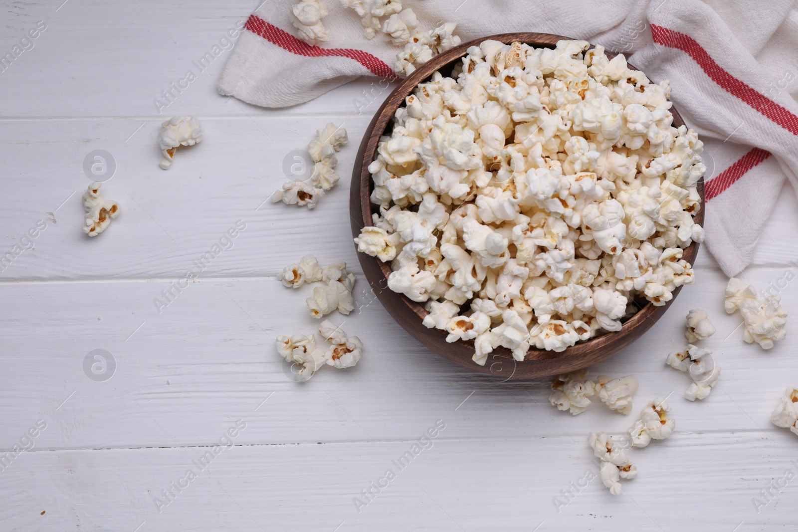 Photo of Tasty popcorn on white wooden table, flat lay. Space for text