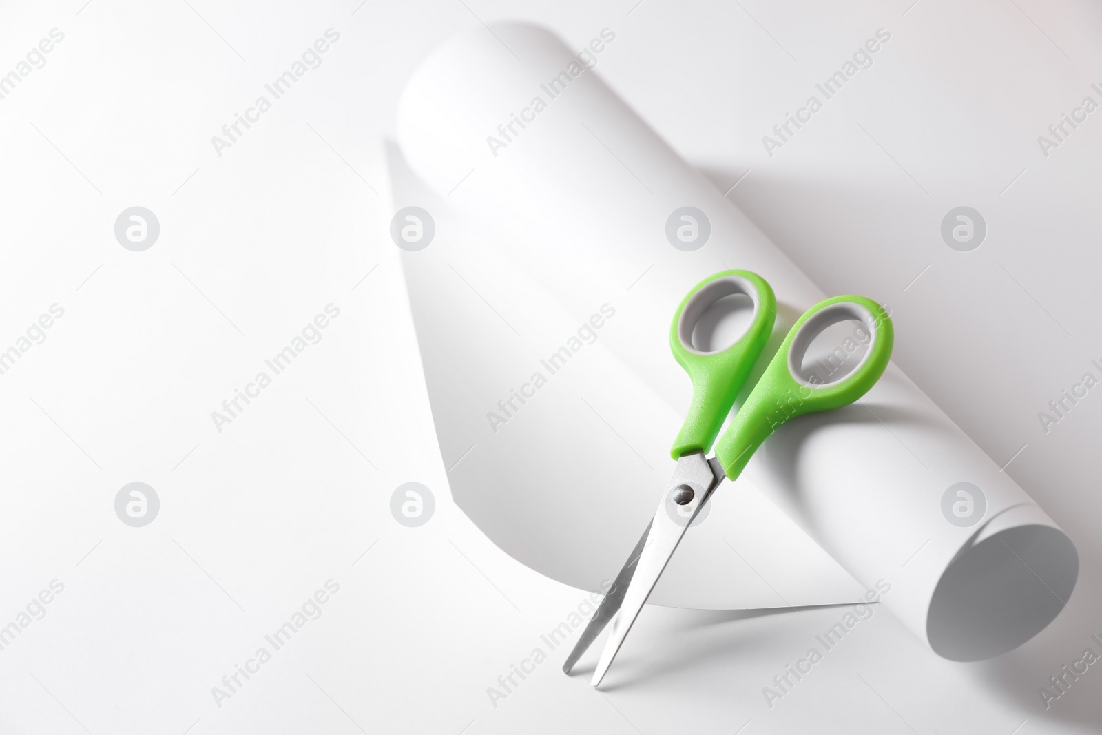 Photo of Green scissors and paper on white background. Space for text