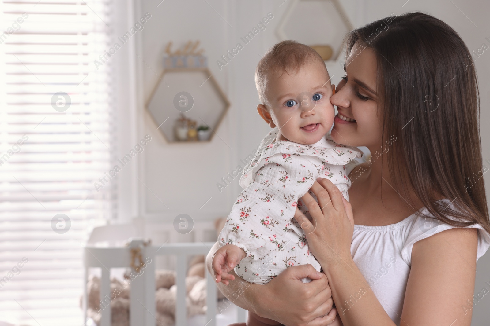 Photo of Happy young mother with her baby daughter in nursery. Space for text