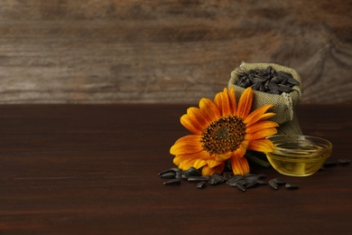 Photo of Sunflower, oil and seeds on wooden table, space for text