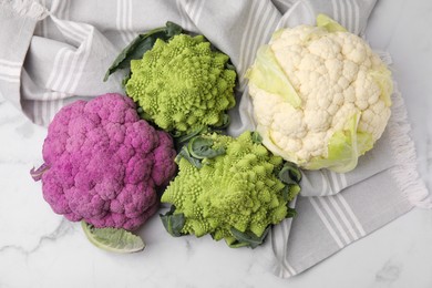 Different fresh cabbages on white marble table, flat lay