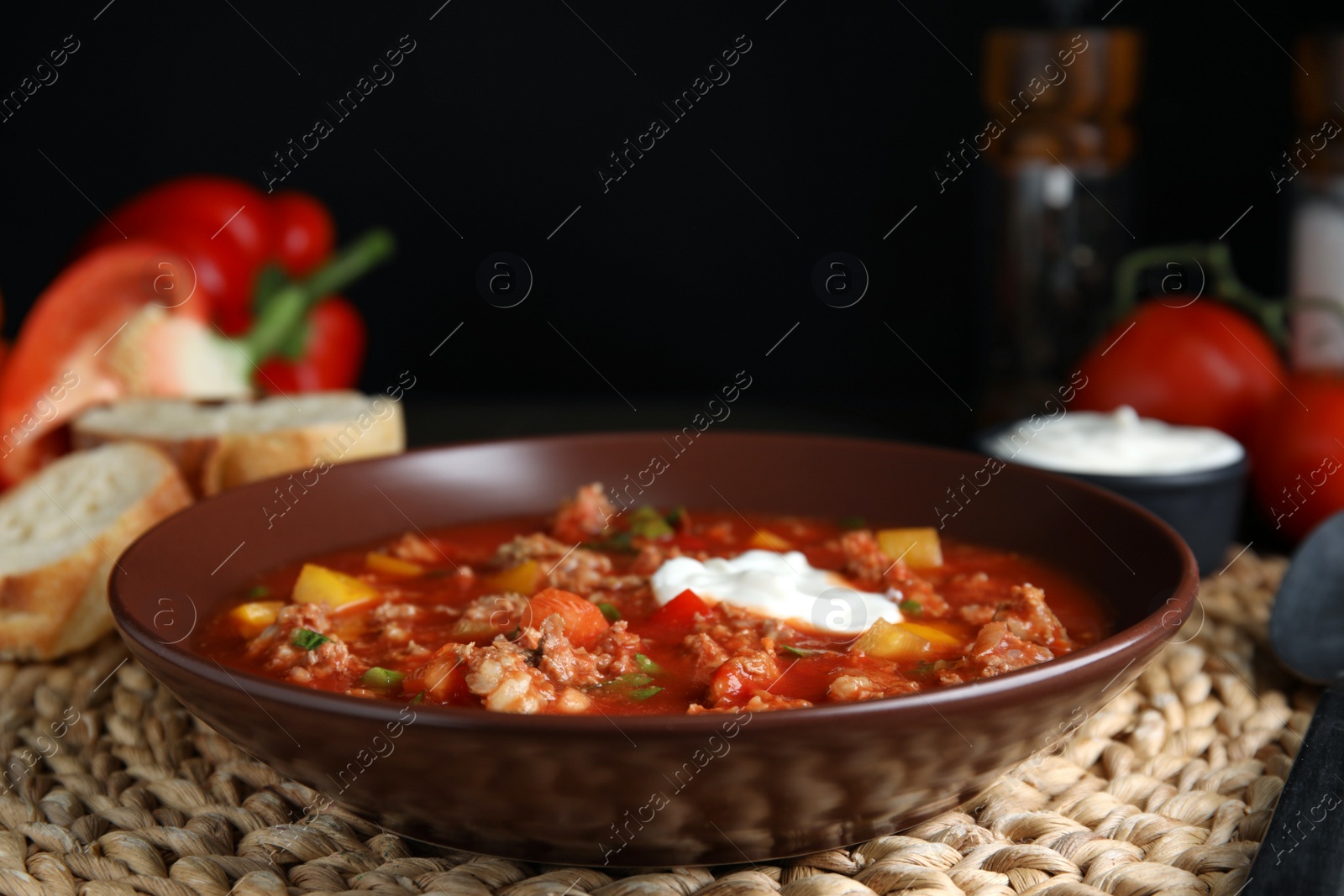 Photo of Bowl of delicious stuffed pepper soup on wicker mat