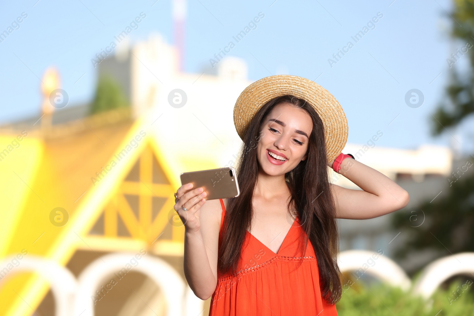 Photo of Happy young woman taking selfie outdoors on sunny day