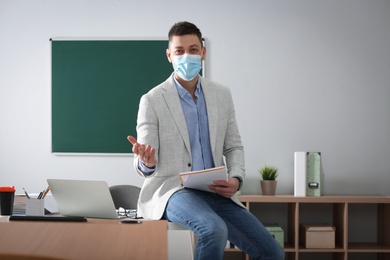Teacher with protective mask conducting lesson in classroom. Reopening after Covid-19 quarantine