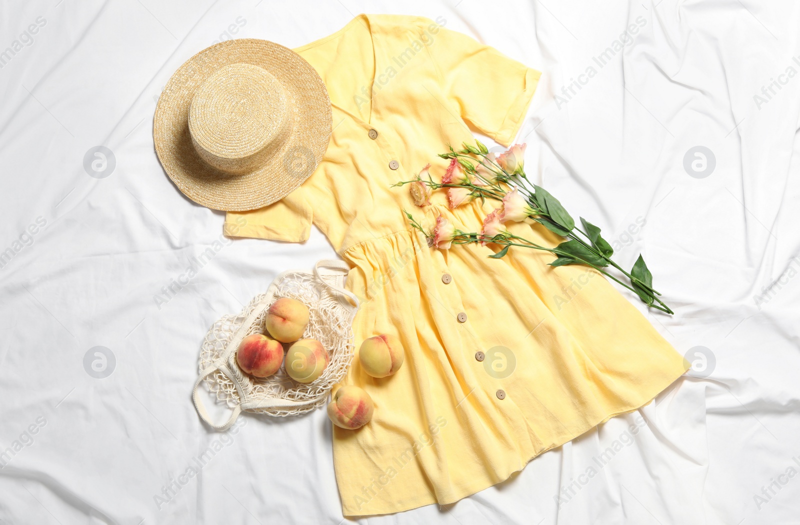 Photo of Flat lay composition with stylish yellow dress on white fabric