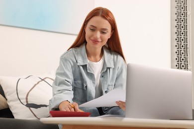 Woman calculating taxes at table in living room