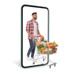 Image of Happy man with shopping cart full of groceries walking out huge smartphone on white background. Advertising design