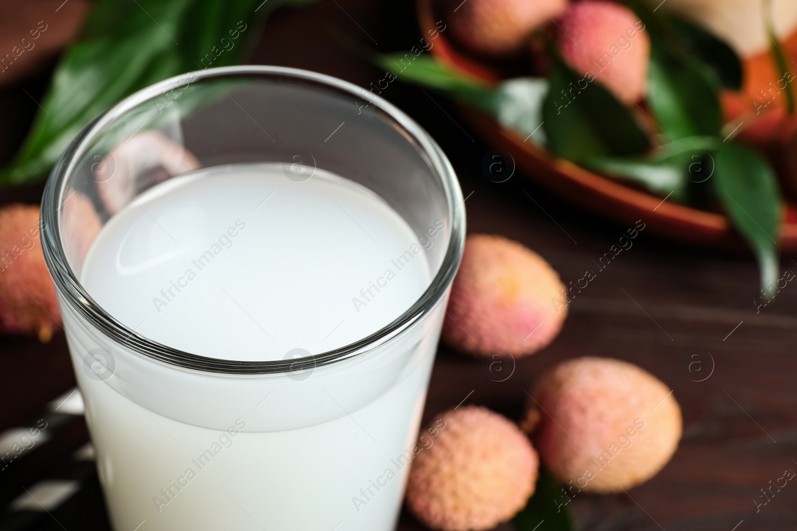 Photo of Freshly made lychee juice on wooden table, closeup. Space for text