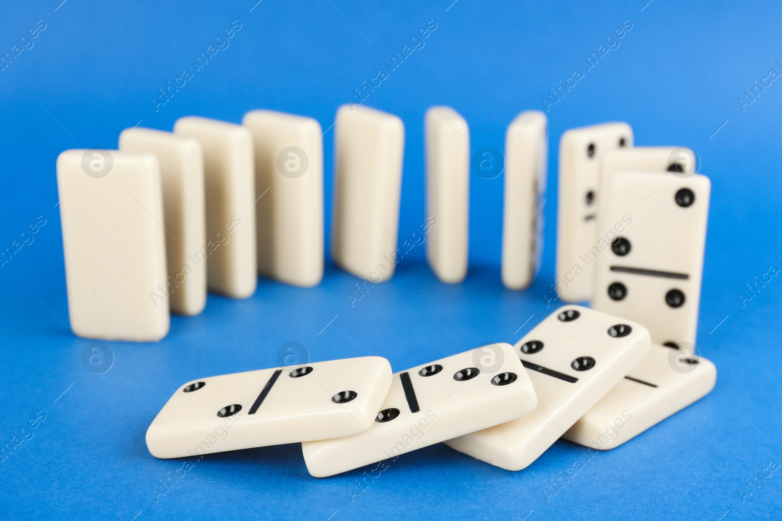 Photo of White domino tiles falling on blue background