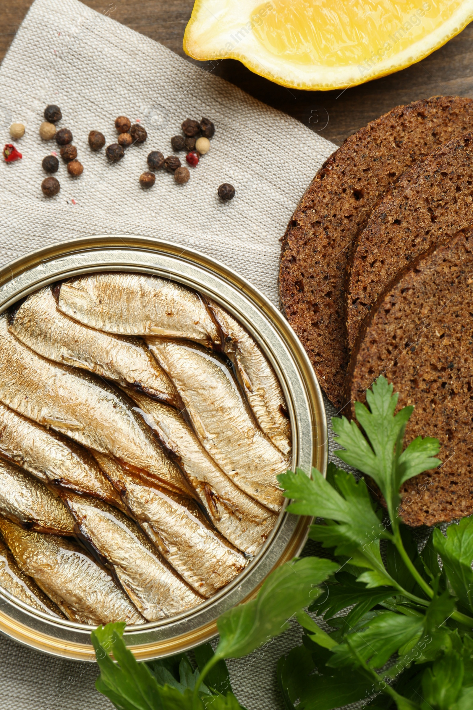 Photo of Tin can with tasty sprats served on table, flat lay