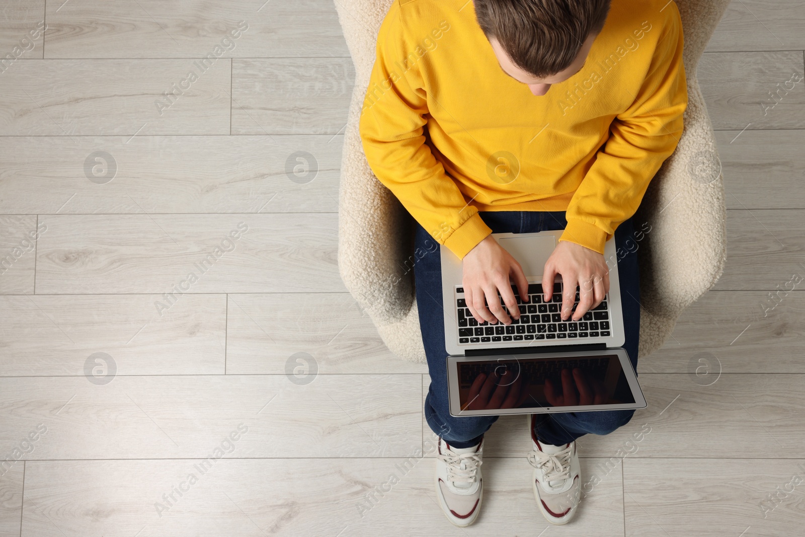 Photo of Man working with laptop in armchair, top view. Space for text