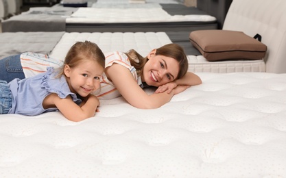 Mother and her daughter lying on new orthopedic mattress in store