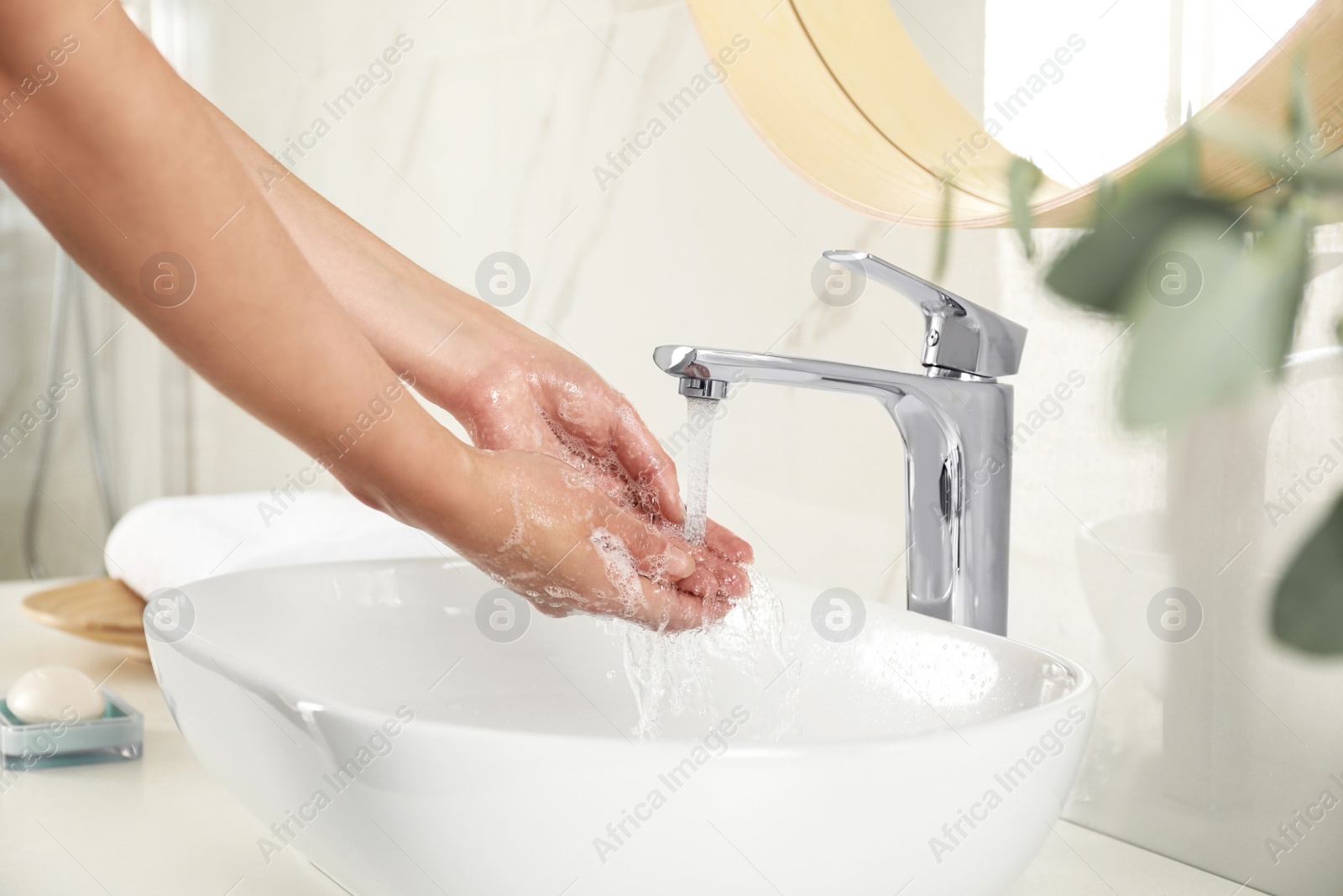 Photo of Young woman washing hands over sink in bathroom, closeup