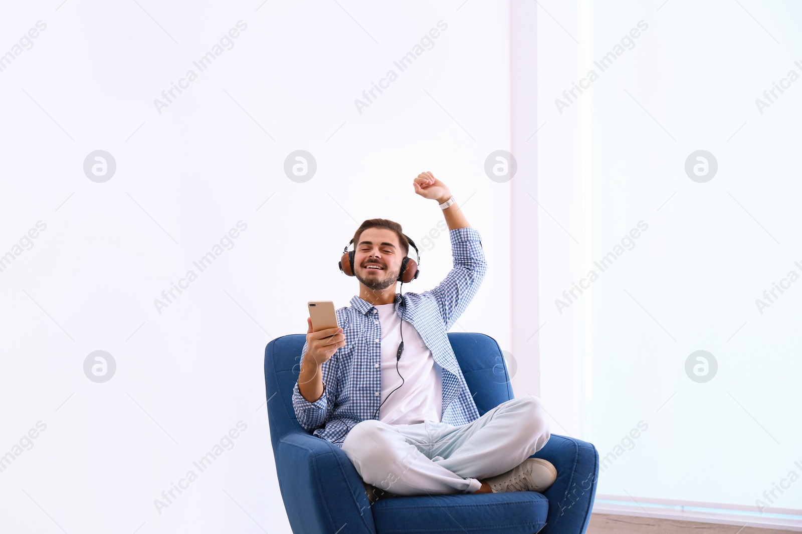 Photo of Handsome young man listening music in armchair indoors
