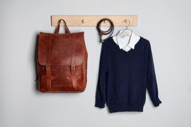 Shirt, jumper and bag hanging on white wall. School uniform