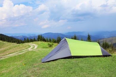 Photo of Small camping tent in mountains on sunny day