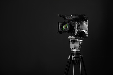 Photo of Modern professional video camera on black background. Space for text