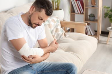 Photo of Man with arm wrapped in medical bandage at home