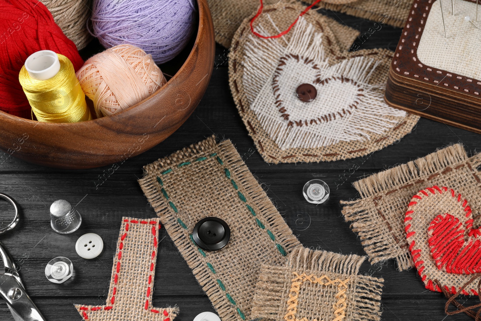 Photo of Pieces of burlap fabric with different stitches on black table, closeup