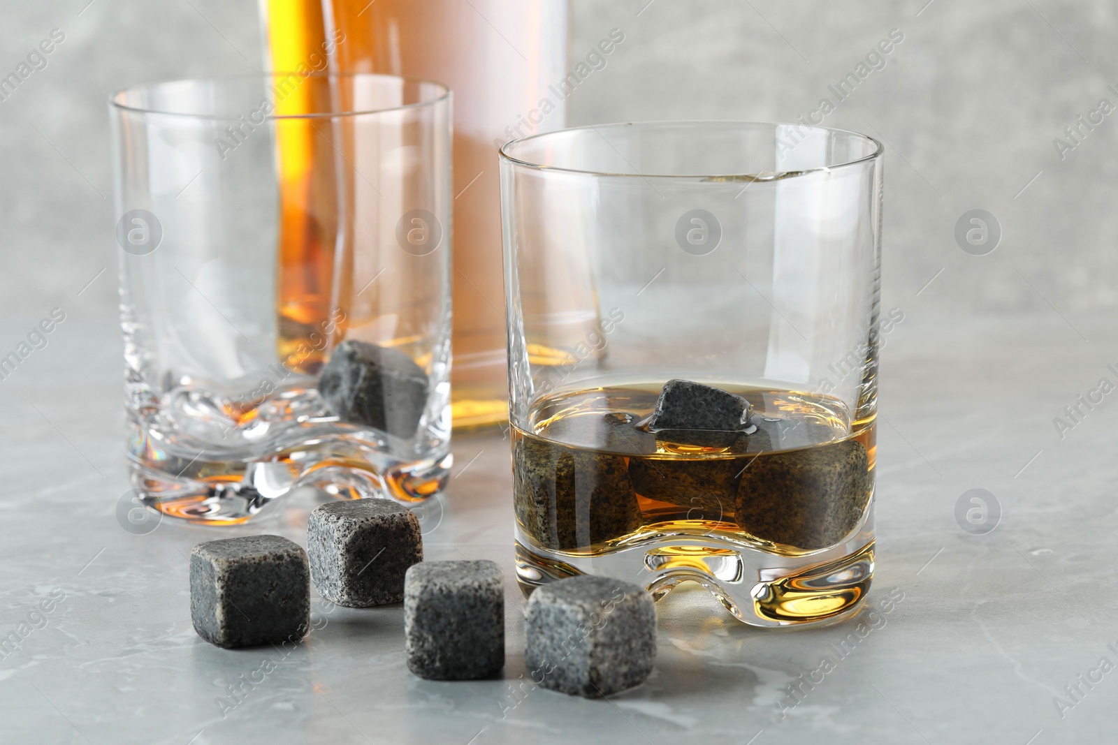 Photo of Whiskey stones and drink on light marble table, closeup