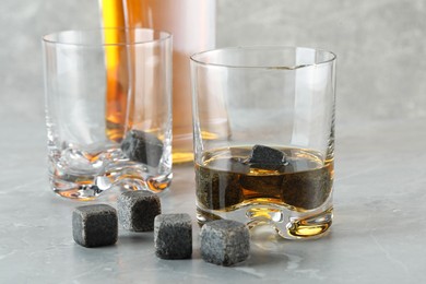 Whiskey stones and drink on light marble table, closeup