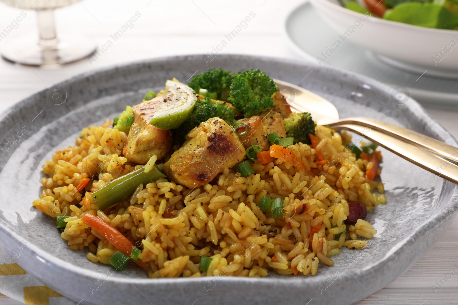Photo of Tasty rice with meat and vegetables in plate served on white wooden table, closeup